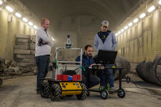 International students working on a robot in an underground corridor.